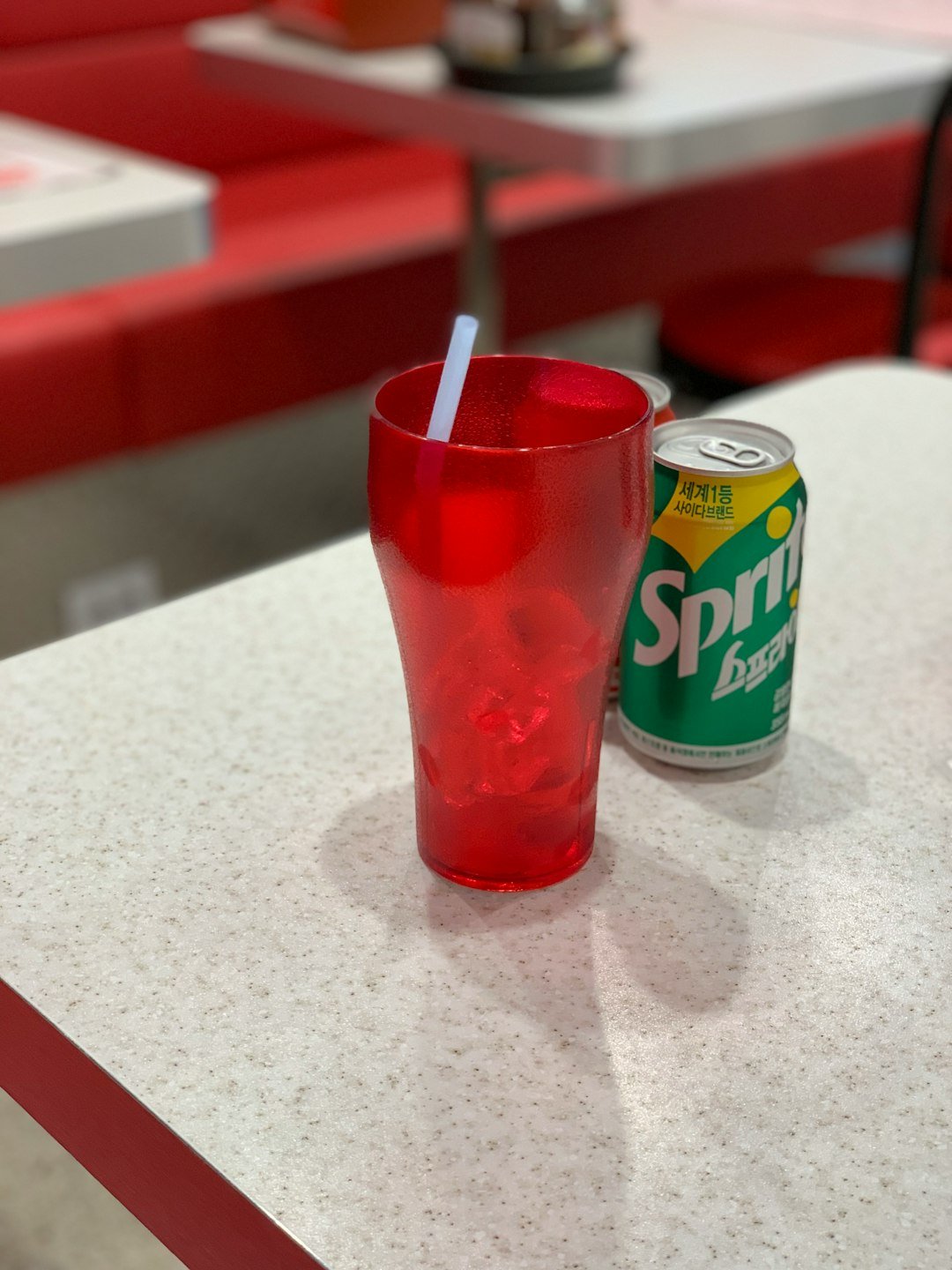 Sprite soda can beside red pint glass