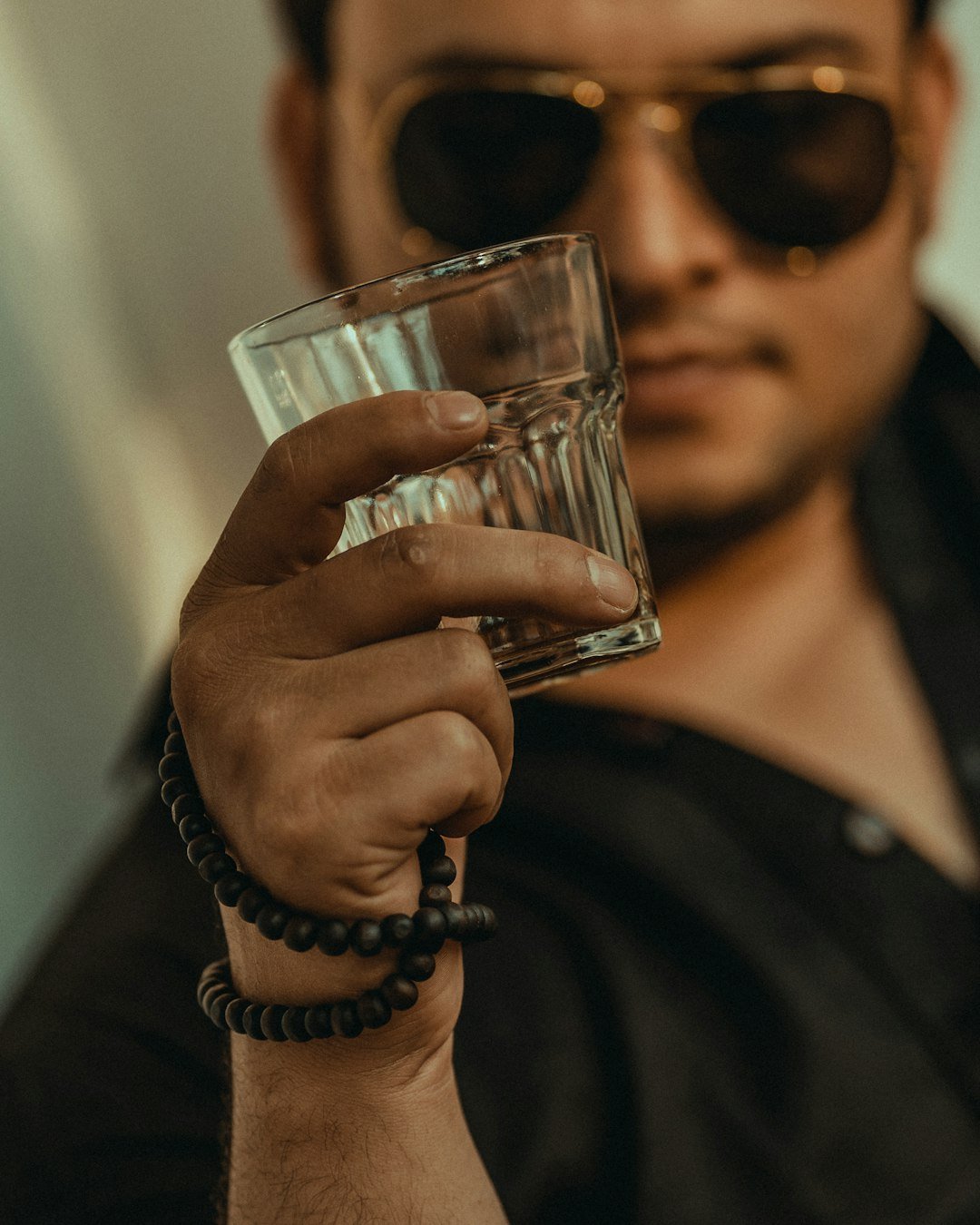 a man in sunglasses holding a glass of water