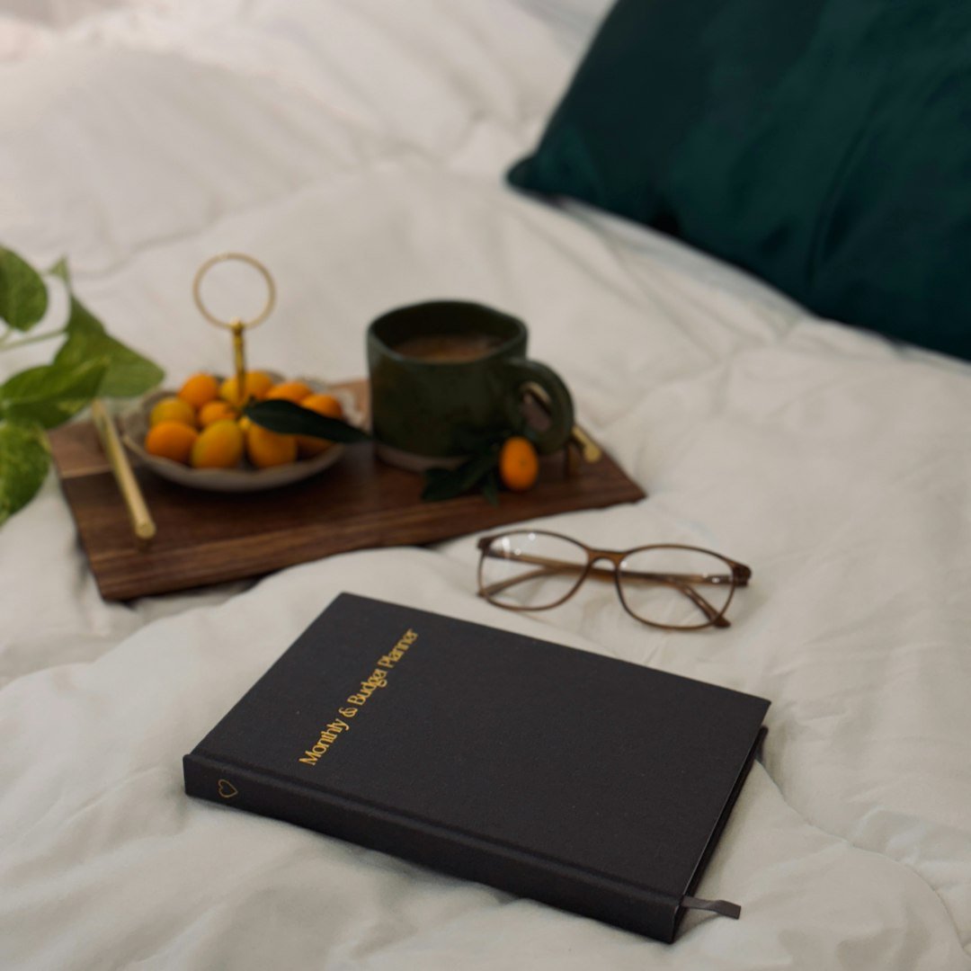 A bed with a tray of oranges, a cup of coffee and a book