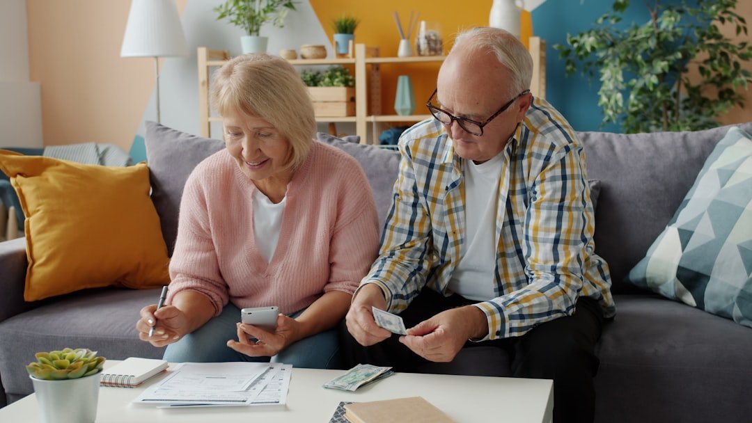 Elderly couple reviews finances at home on couch.