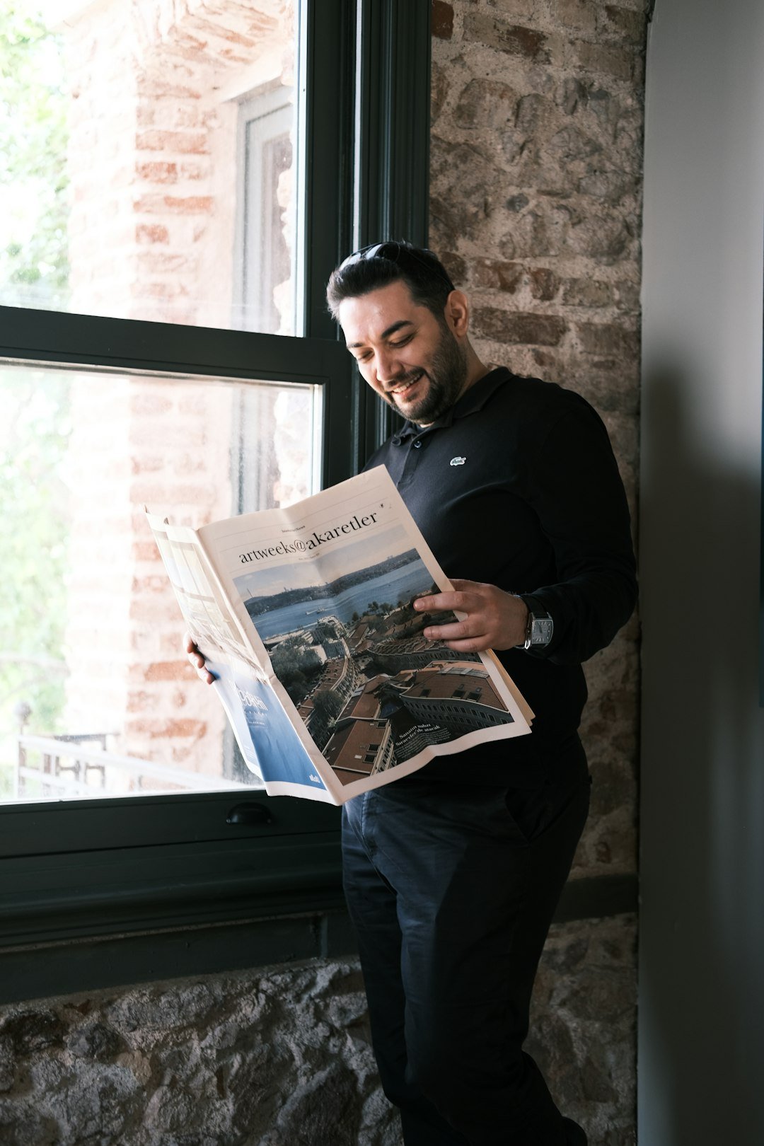 a man standing in front of a window reading a newspaper