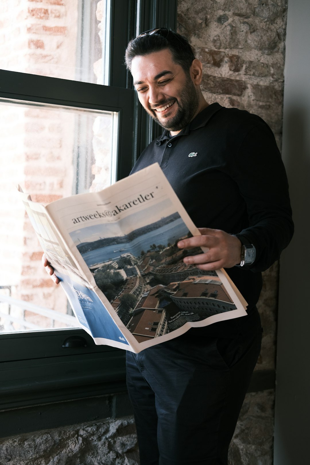 a man in a black shirt is reading a newspaper