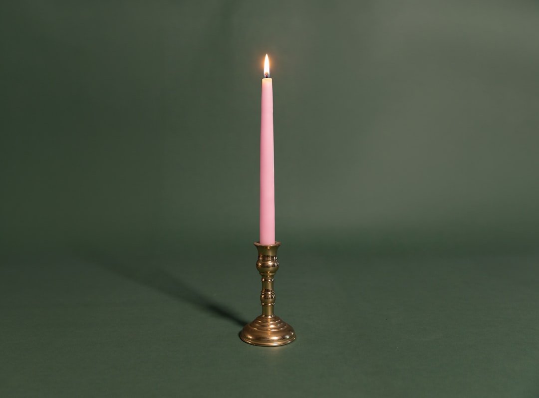 A single pink candle sitting on top of a table