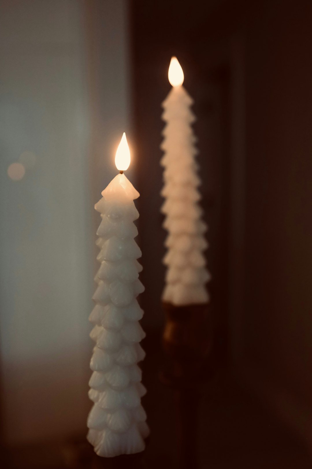 Two white candles sitting on top of a table
