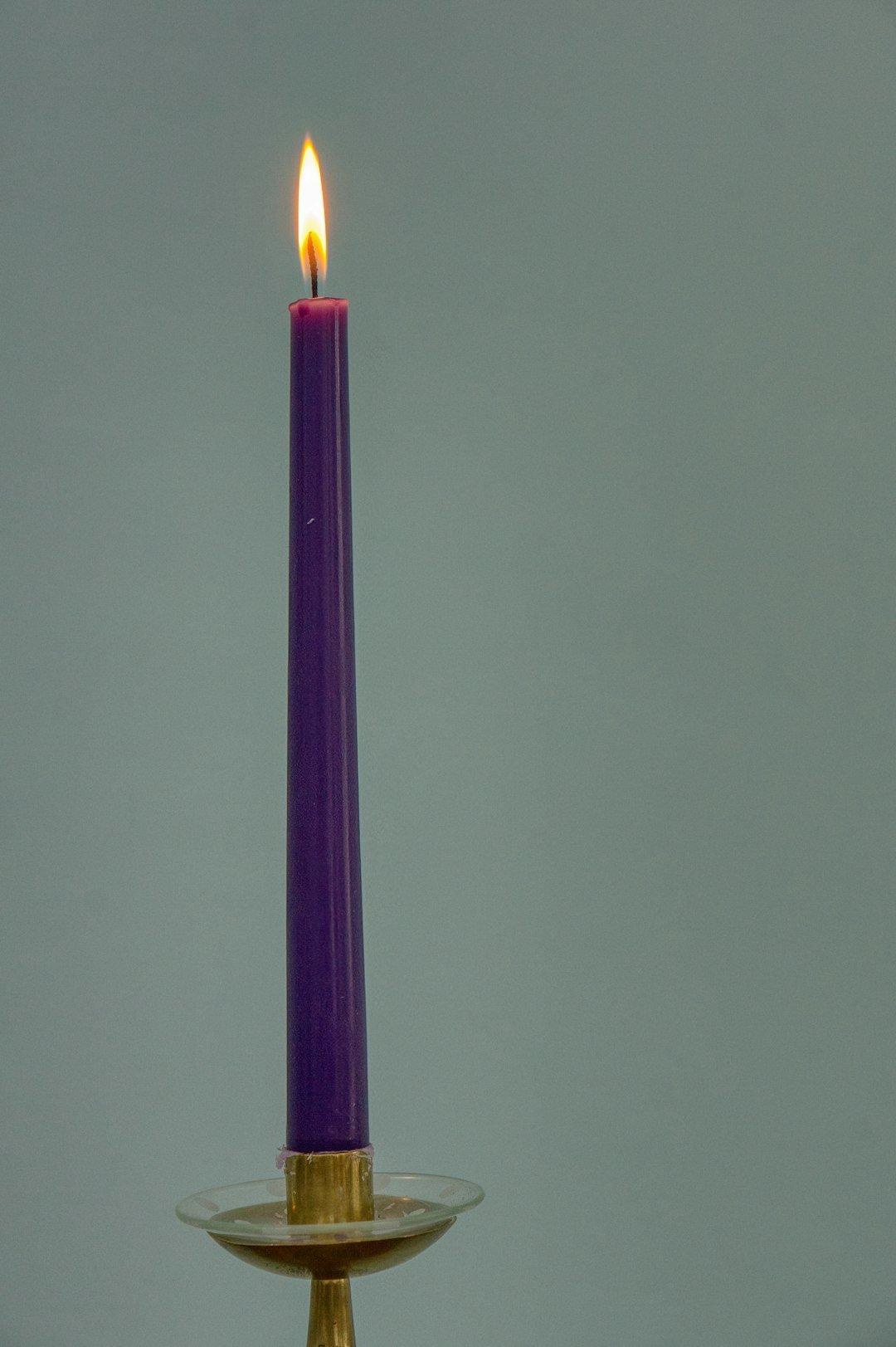 A single purple candle is lit in a candle holder