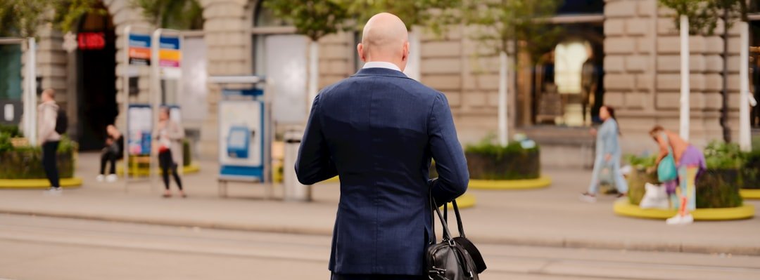Man in suit walks with bag on city street.