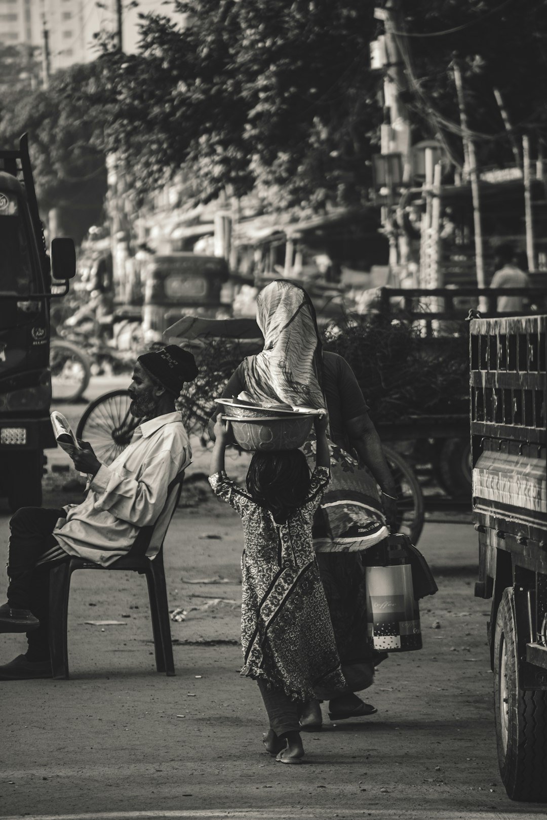 Child carries bowl on head in busy street.