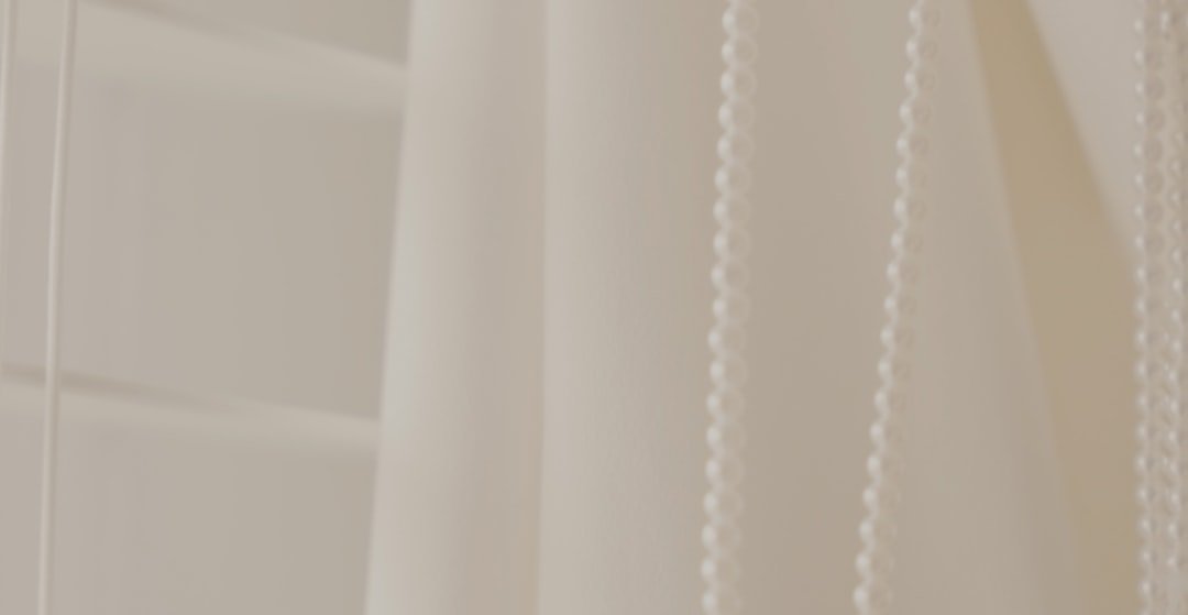 a close up of a white curtain with beads hanging from it