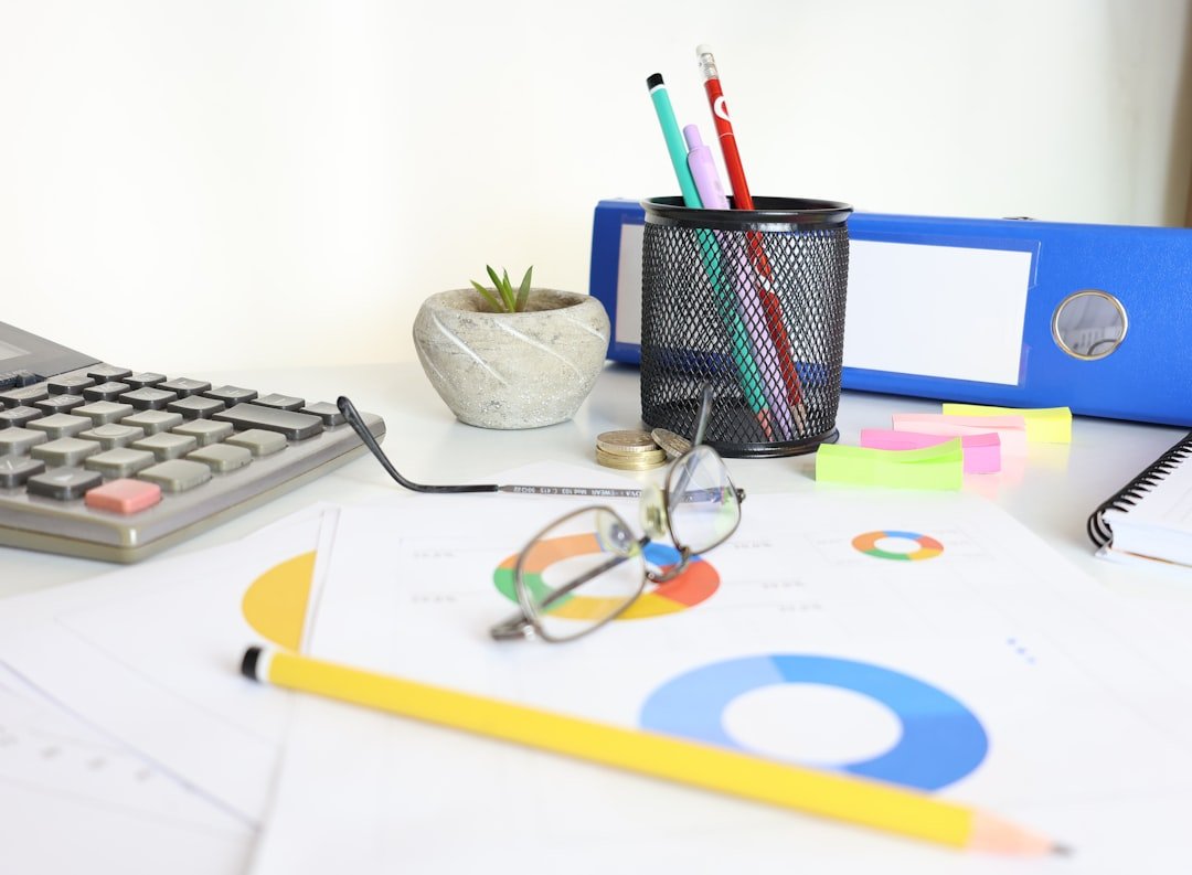 Desk with calculator, glasses, charts, and office supplies