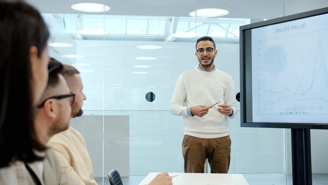 Man presents to colleagues in a modern office meeting.