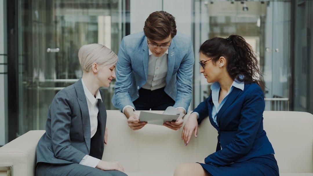 Three business people looking at tablet on sofa