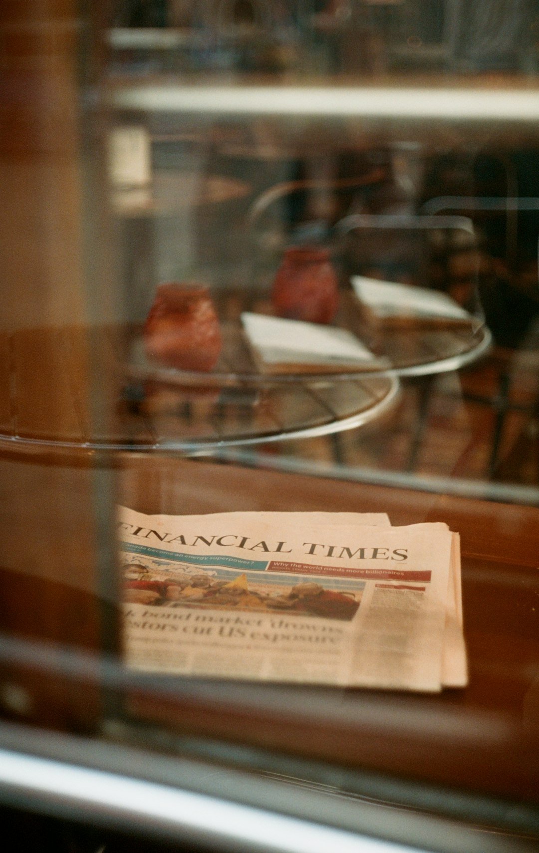 Financial times rests near pastry in a display case.