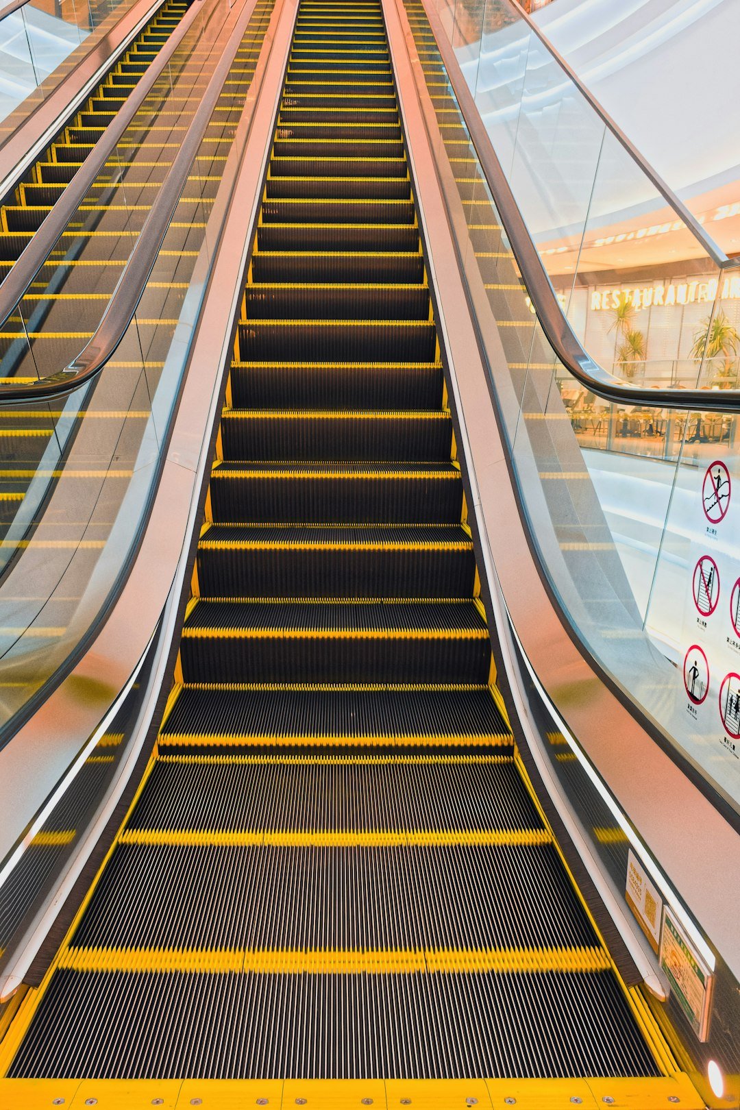 An empty escalator going upwards with yellow stripes.