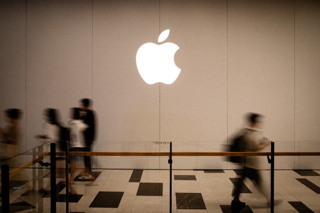 People walk past a large glowing apple logo.