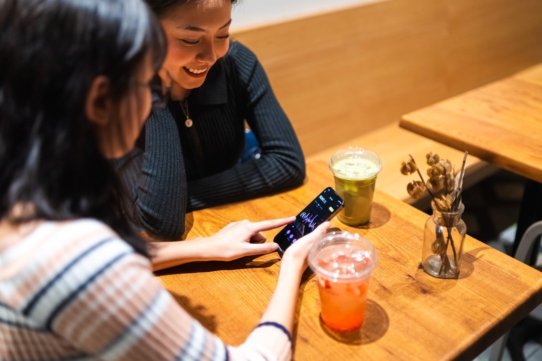 Two women looking at a smartphone at a smartphone together