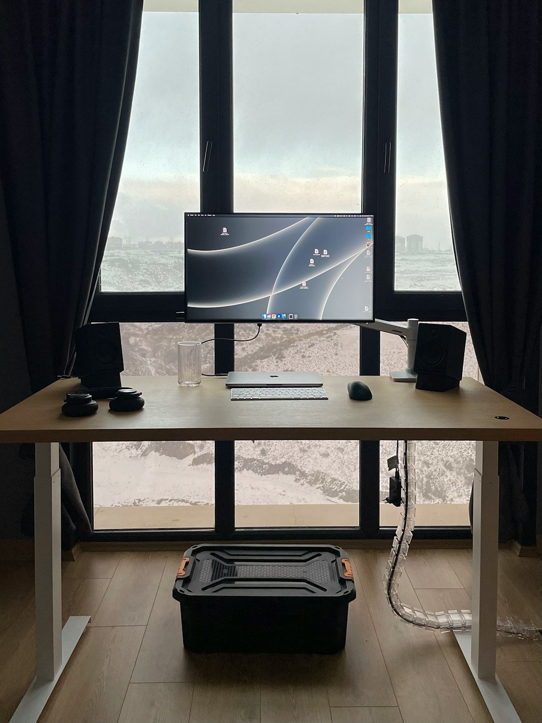 a desk with a computer on it in front of a large window