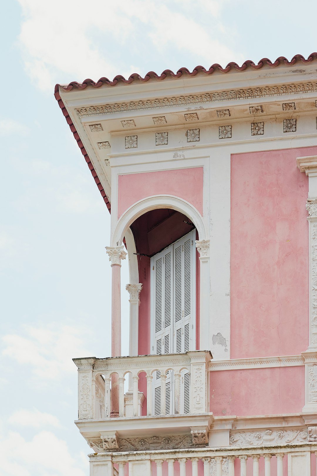 A pink and white building with a balcony